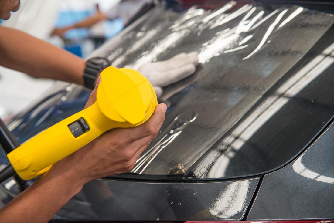 Picture of yellow heat gun applying tint on a car